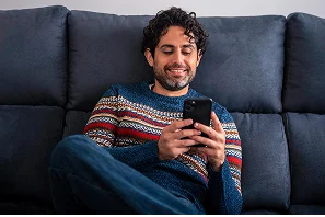 Man checking currency rates on his phone at home
